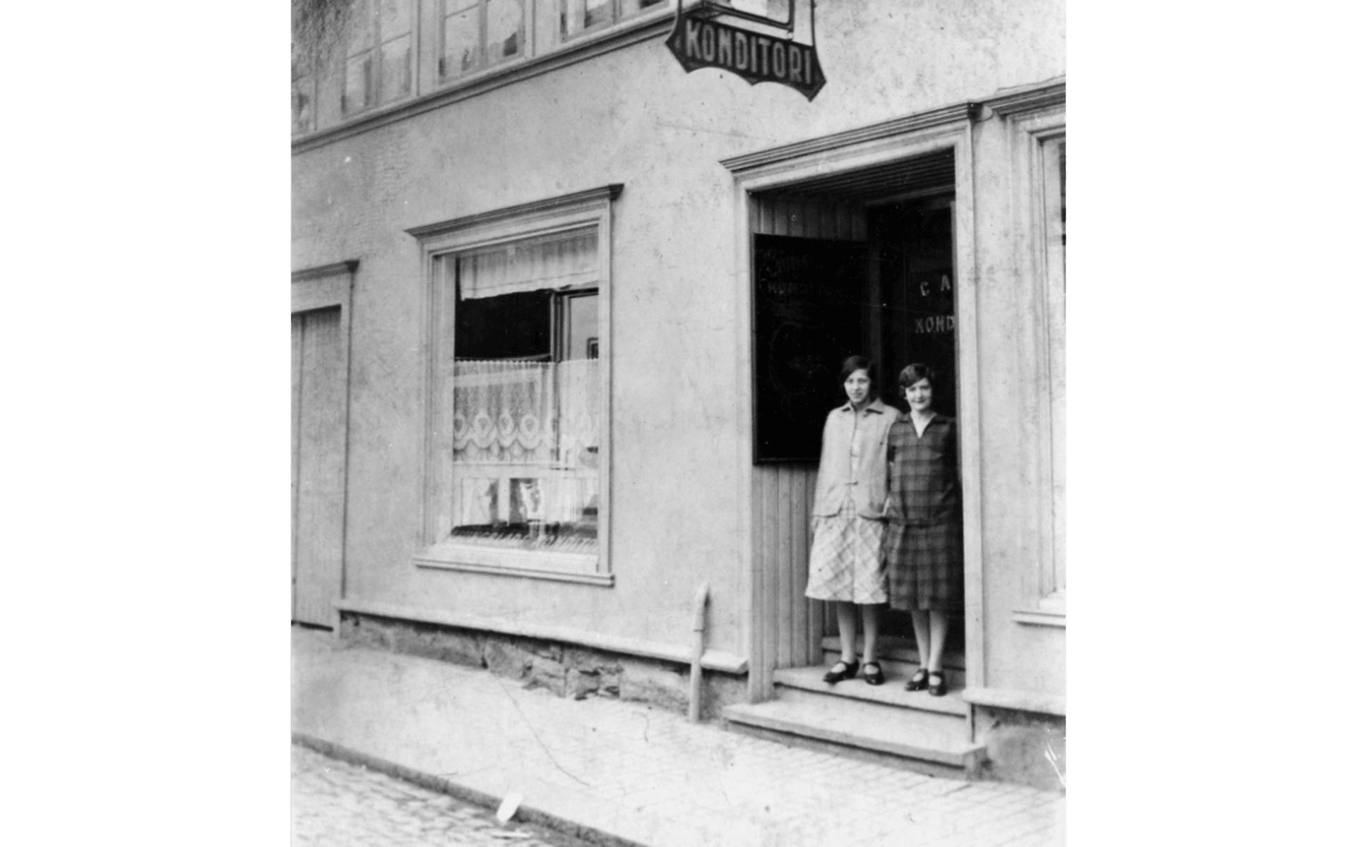 Ljungblads konditori på Kungsgatan, kvarteret Hjorten 3. Två kvinnor står i entrén. Till vänster Judith Ljungblad, född Andersson. På 1930 talet flyttade konditoriet till Lilla torget och stängde 2017. Fotot från omkring 1920-talet.