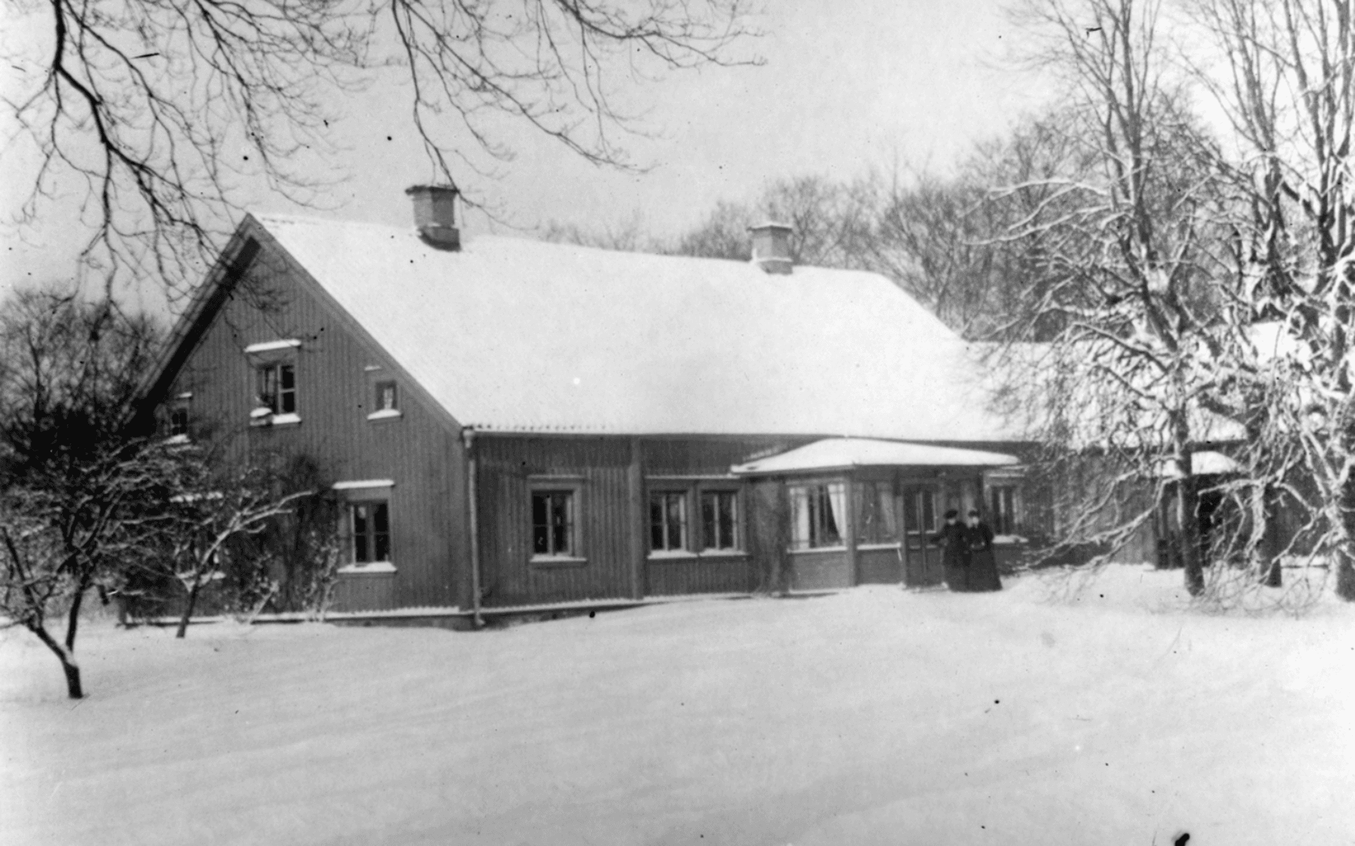 Gamla prästgården med ett snötäckt tak och marken likaså. Fotografering - 1890 — 1900.