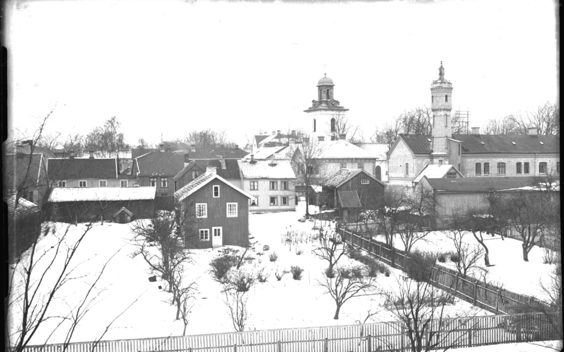 Fotografi taget från Bomullsväveriets tak med utsikt mot kyrkan och Väktaregården med dess torn. Fotografering - 26 februari 1924.
