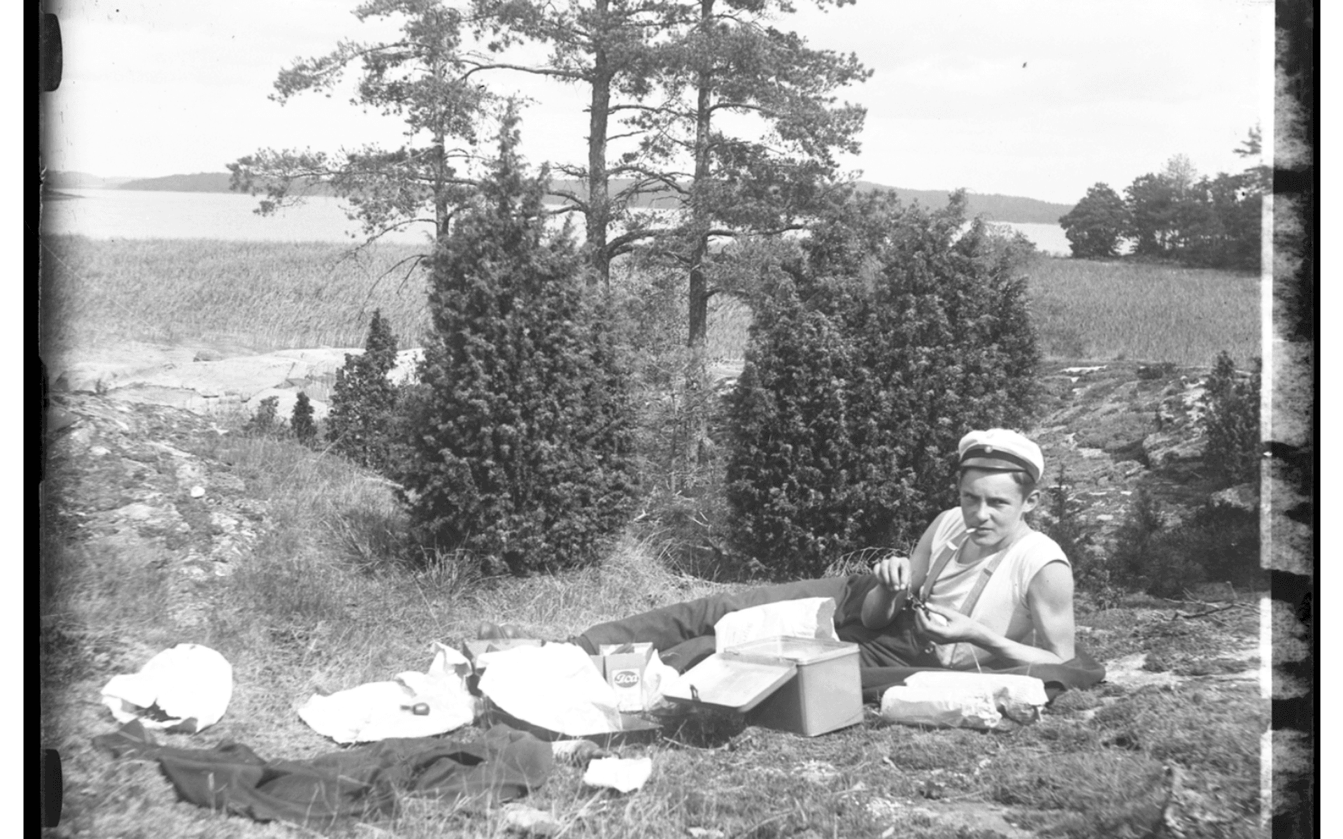 Folke Olsson röker en cigarett vid fikapaus från fiskande vid Norseskären, Mjörn. Fotografering - 1917.
