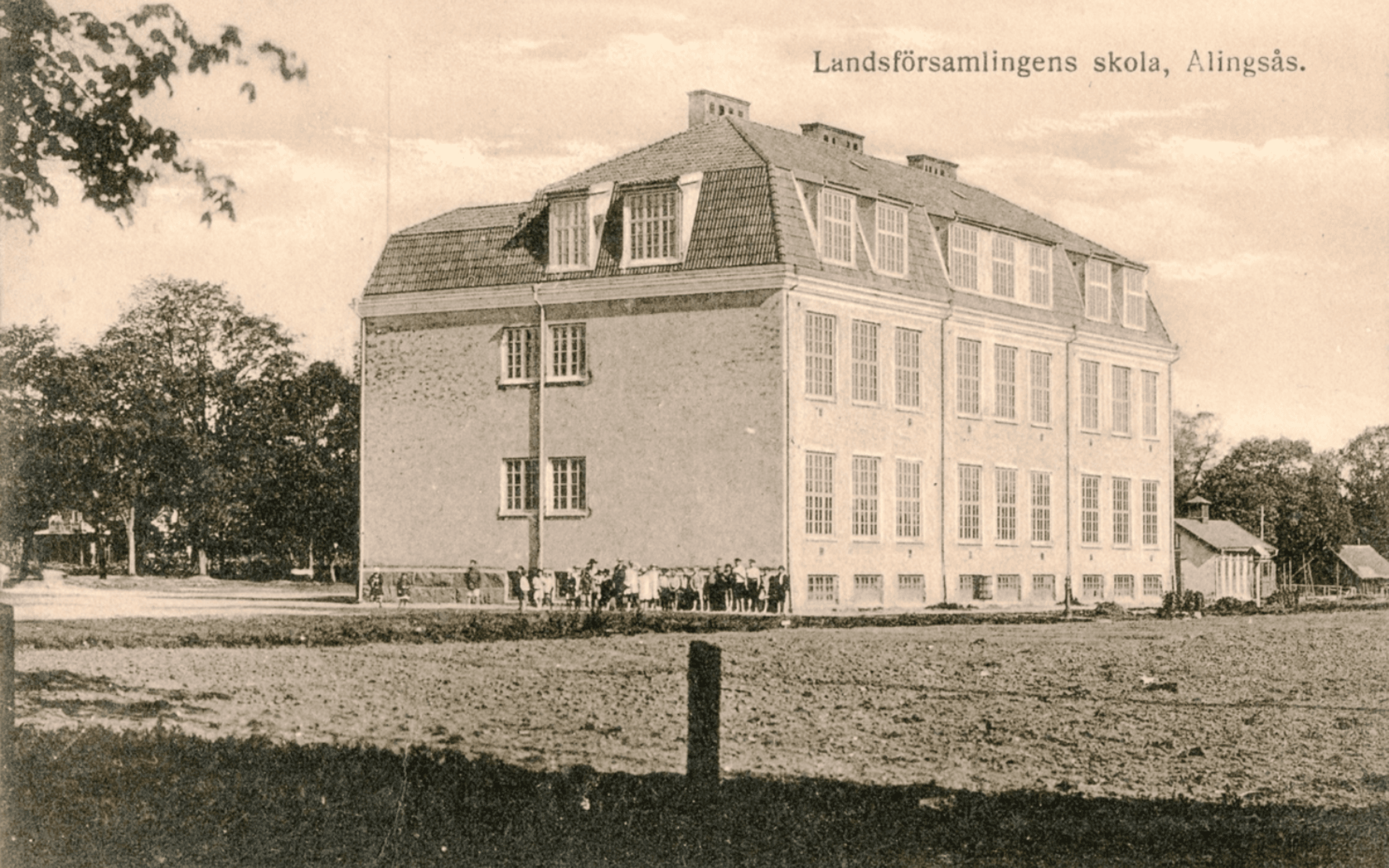 Vykort av Landsförsamlingens skola, invigt 1917, nu Afzeliiskolan. Skolbyggnaden, en samling elever och andra står utanför skolan. 