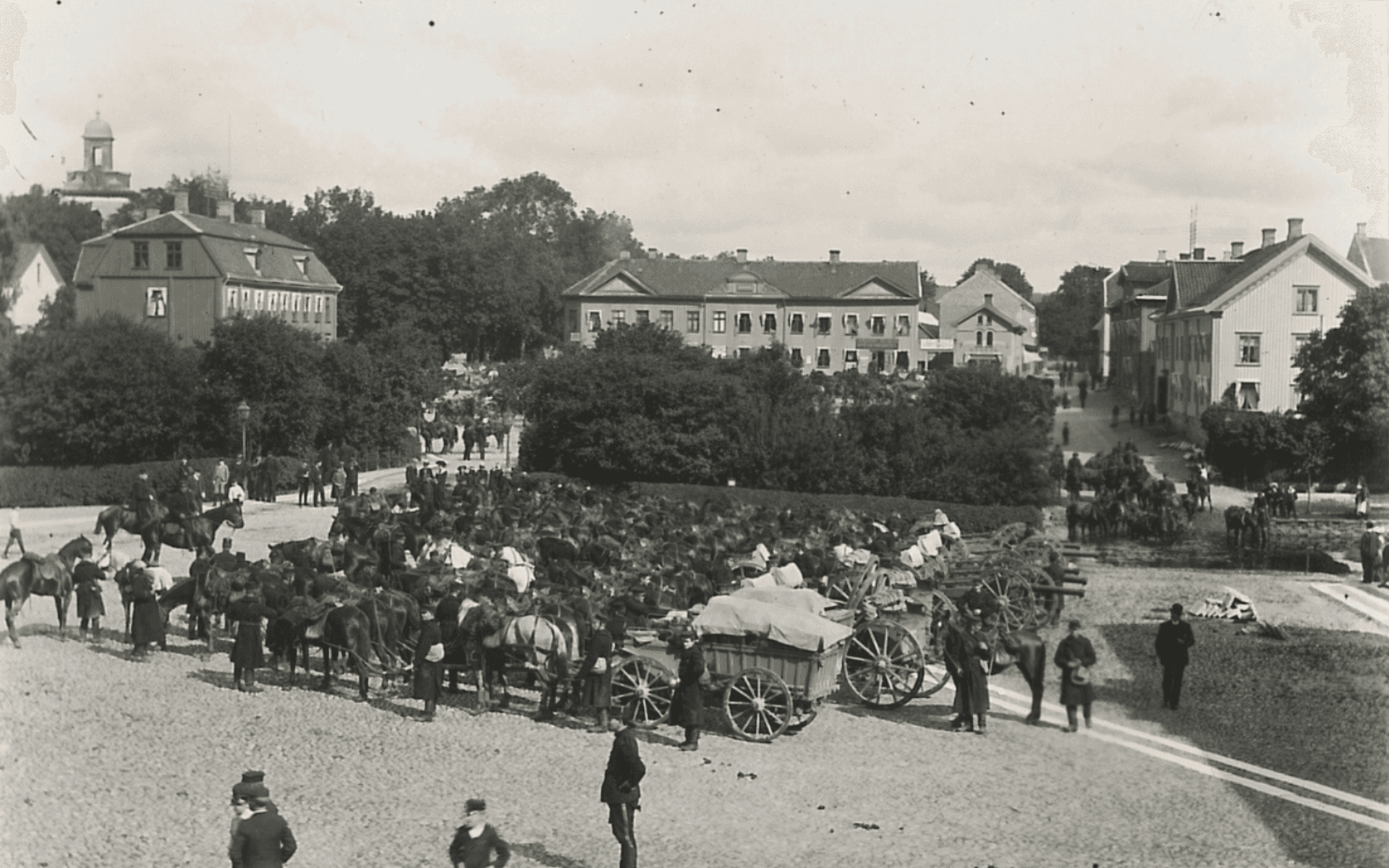 Kungliga Första Göta artilleriregemente rastar på Lilla Torget på marsch till Tåga hed, sommaren 1900. I bakgrunden syns Stora torget. Fotografering - 1900.
