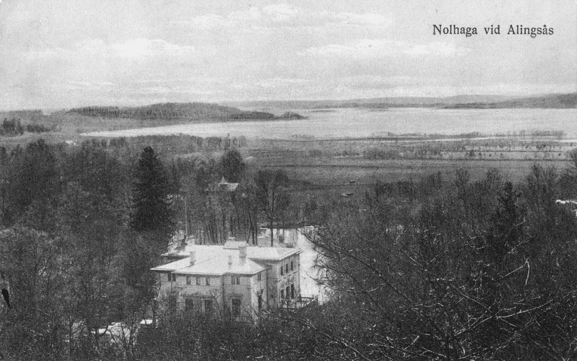Vykort med Nolhaga slott i förgrunden och sjön Mjörn i bakgrunden, däremellan träd och ängar. Fotografiet taget från Nolhaga berg. Fotografering - 1895-1925.