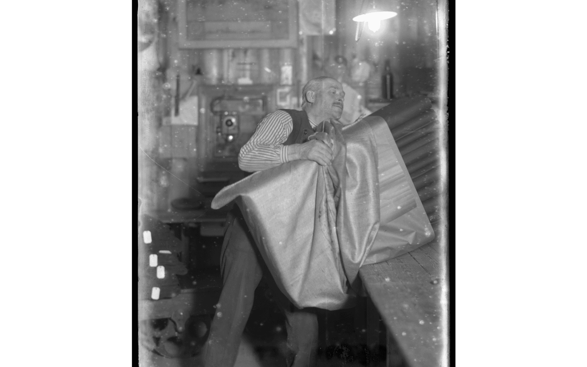 Fabriksarbetare Axel Wiberg packar färdiga textilier vid Alingsås Bomullsväveri. Fotografering - 1923