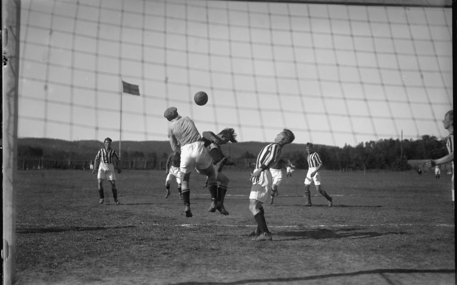 Situationsbild från en fotbollsmatch. Spelarna i randiga tröjor hör till Alingsås Idrottsförenings fotbollslag. Fotografering - 14 juli 1929.
